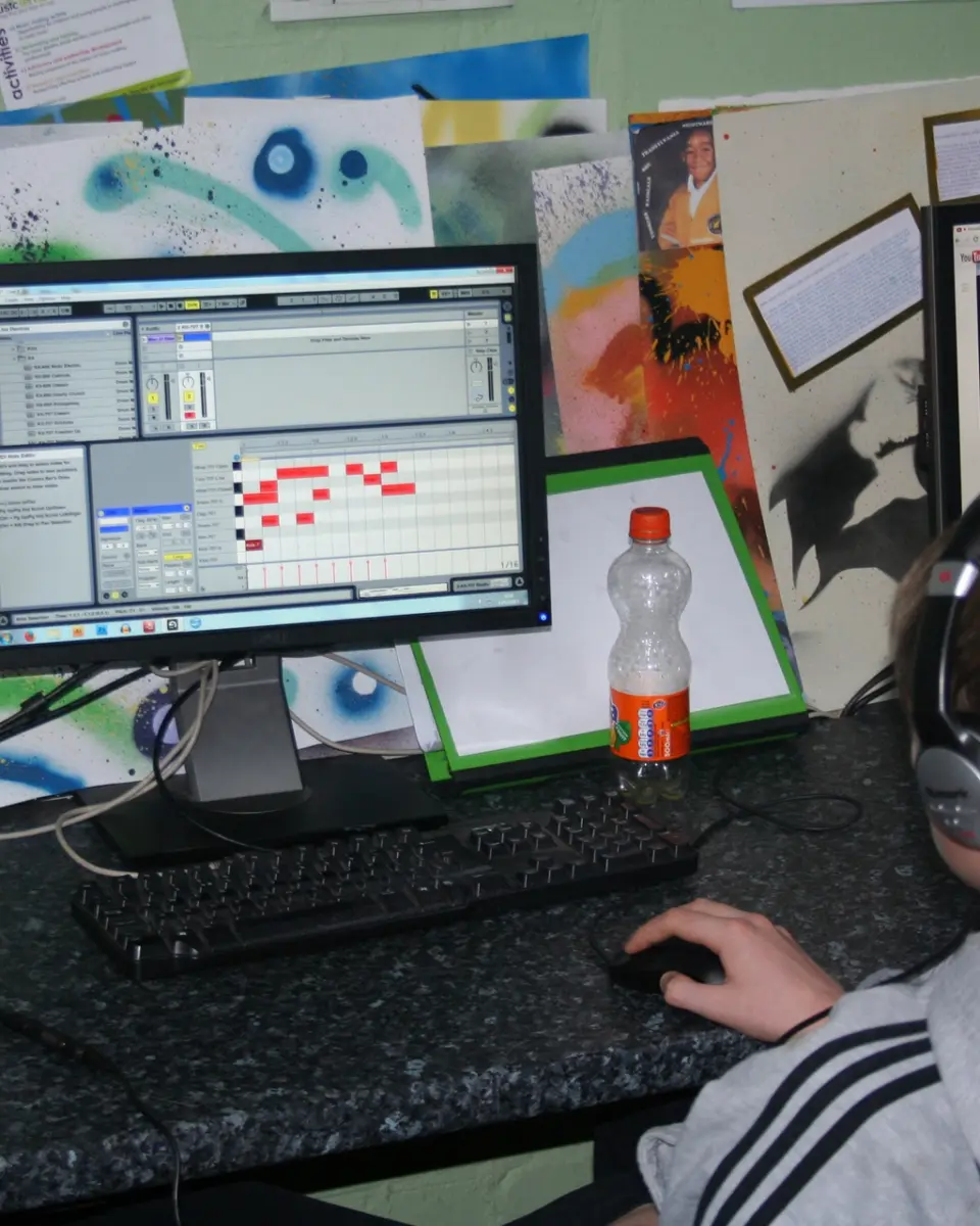 A young person wearing headphones making music on a computer in the SEND studio