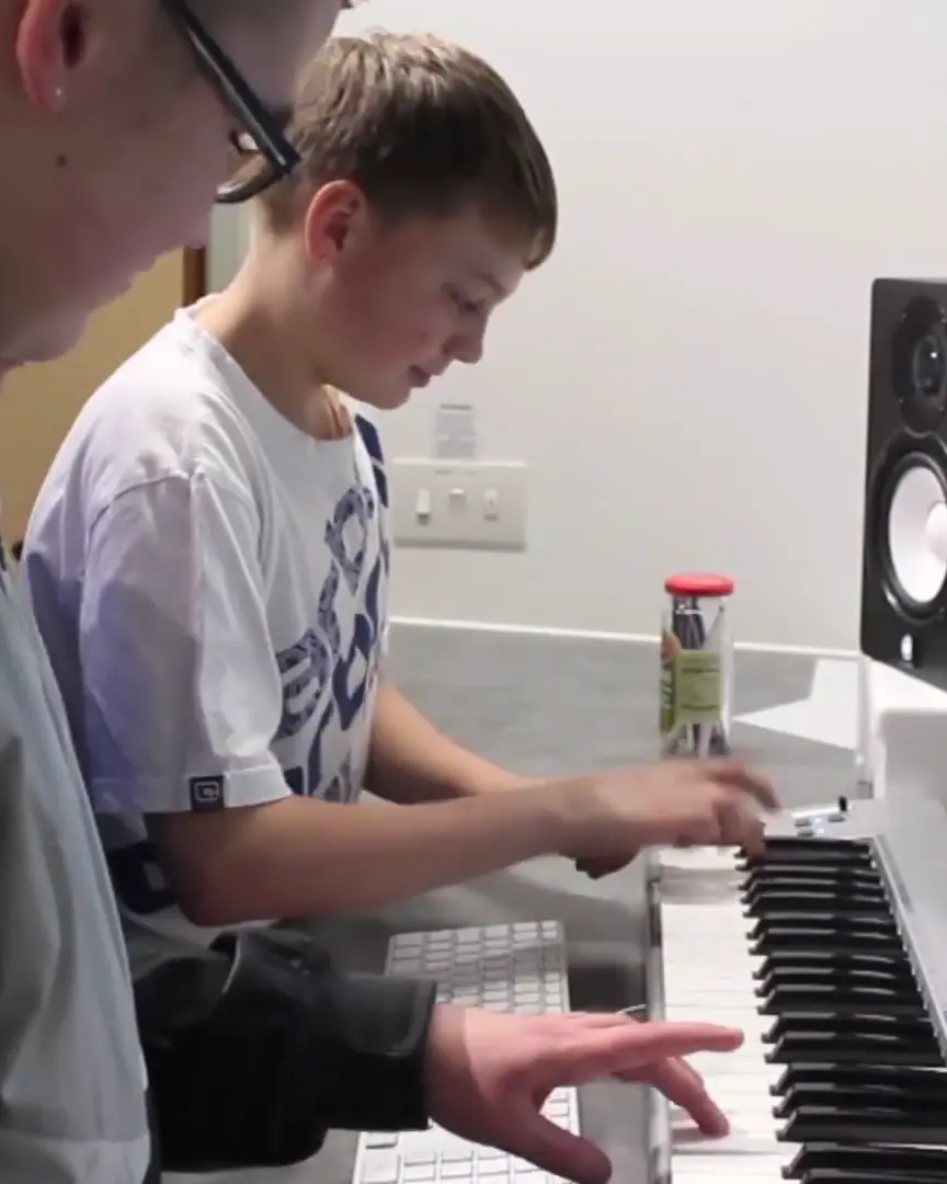 Young people playing a keyboard and producing music in the studio