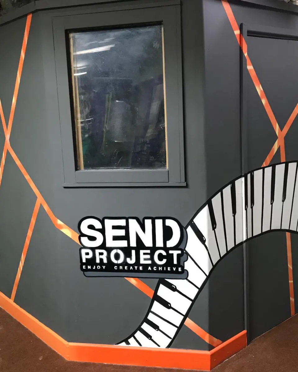 The SEND Project recording booth, painted with an orange outline and a piano-key mural