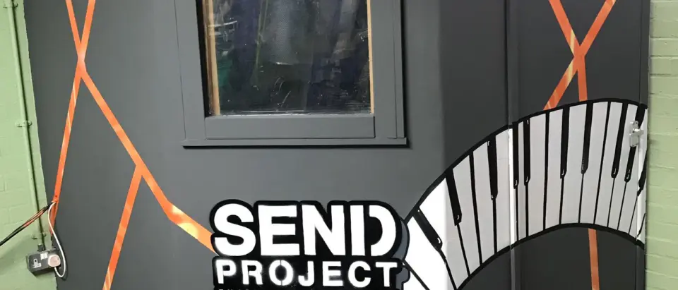 The SEND Project recording booth, painted with an orange outline and a piano-key mural