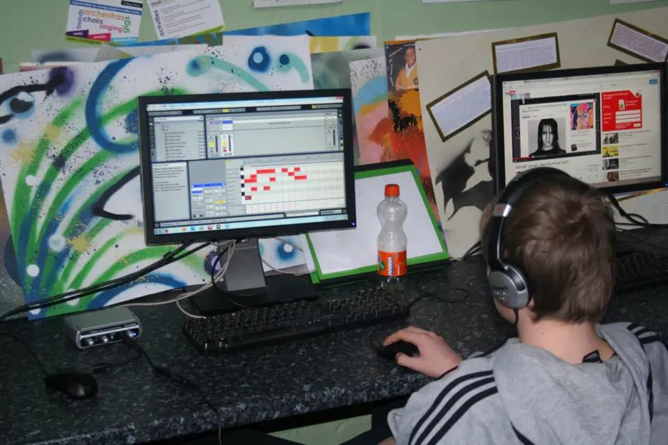 A young person wearing headphones making music on a computer in the SEND studio