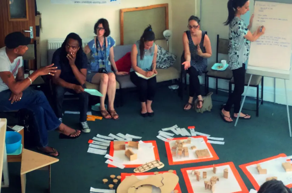 A group sitting in a circle during a SEND Project workshop, with craft materials laid out on the floor