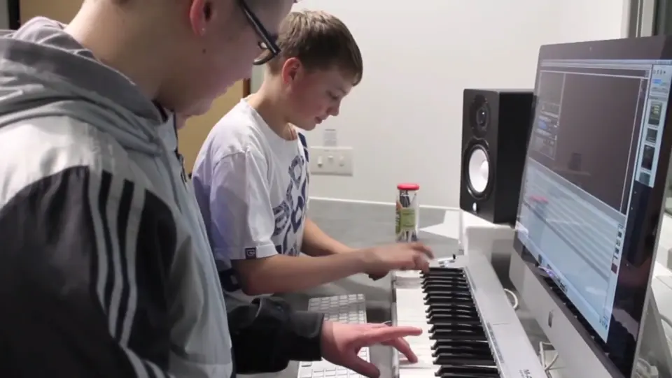 Young people playing a keyboard and producing music in the studio